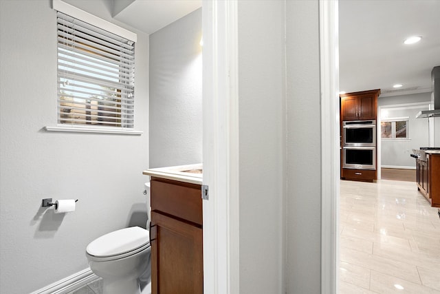 bathroom with toilet, recessed lighting, vanity, and baseboards