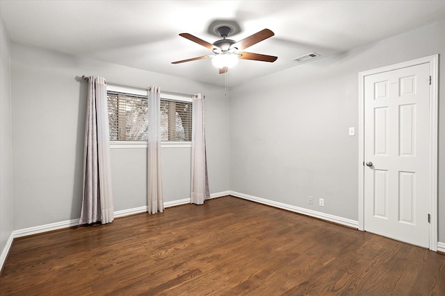 unfurnished room with a ceiling fan, dark wood-style flooring, visible vents, and baseboards