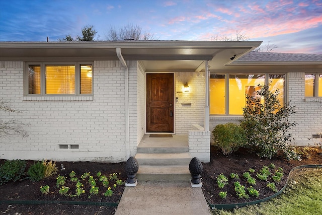 exterior entry at dusk with brick siding and crawl space