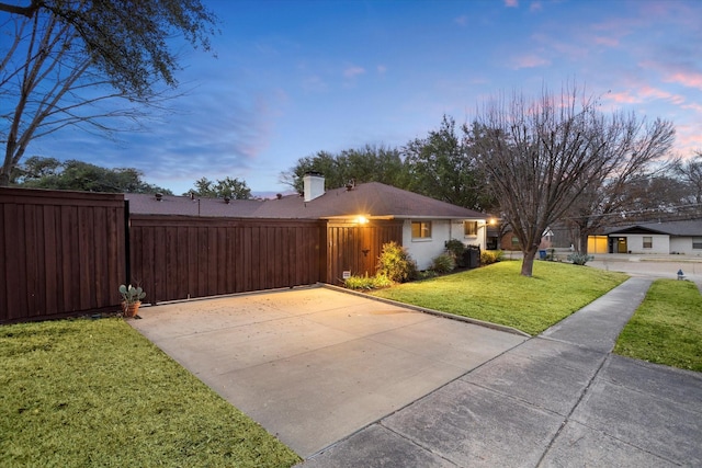 view of front facade with driveway, a chimney, fence, and a front lawn