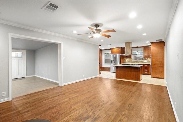 kitchen with a center island, stainless steel refrigerator with ice dispenser, light countertops, visible vents, and island range hood