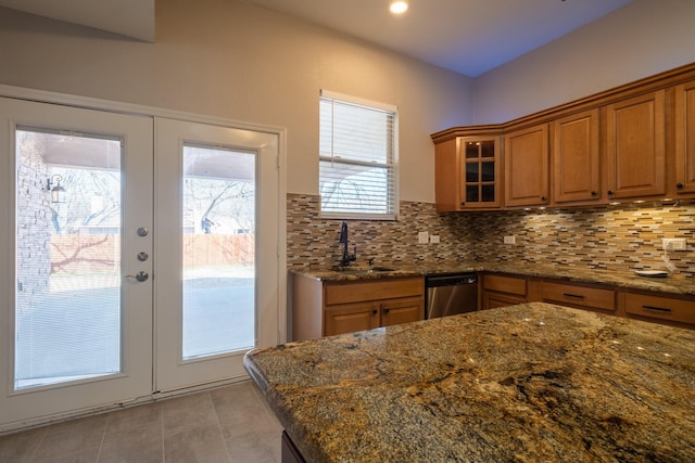 kitchen with decorative backsplash, brown cabinetry, a sink, and stainless steel dishwasher