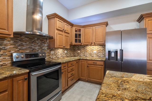 kitchen with appliances with stainless steel finishes, stone counters, wall chimney range hood, and tasteful backsplash