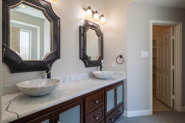 full bathroom featuring double vanity, baseboards, a sink, and tile patterned floors