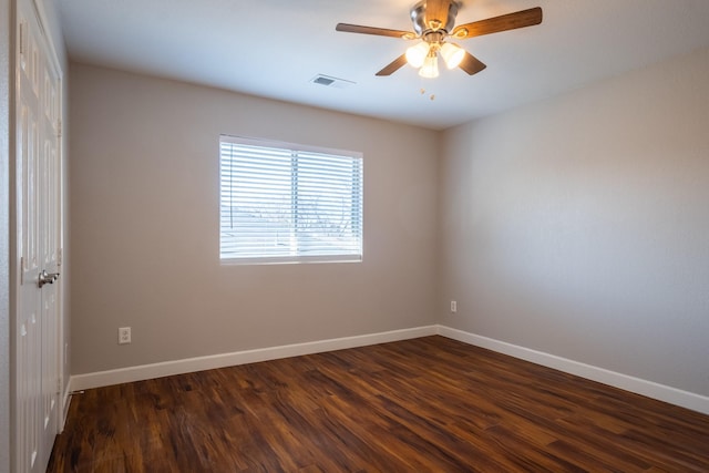 empty room with baseboards, visible vents, and dark wood-type flooring