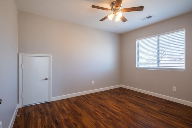 unfurnished room with a ceiling fan, dark wood-style flooring, visible vents, and baseboards