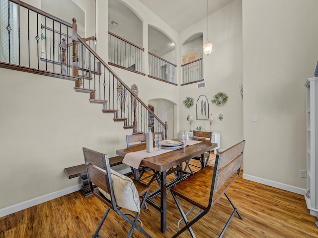 1009 Lake Forest Trl, Little Elm, TX 75068 - dining room featuring baseboards, arched walkways, wood finished floors, stairway, and a high ceiling