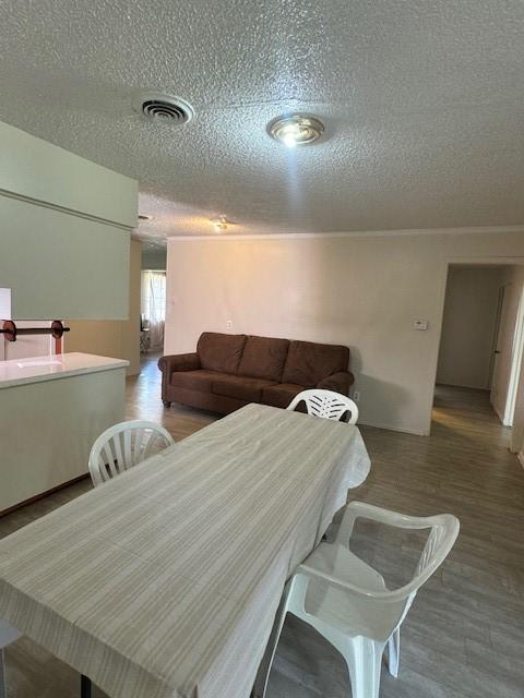 dining area featuring a textured ceiling, wood finished floors, and visible vents