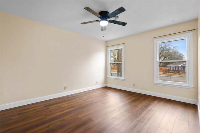 empty room with ceiling fan, baseboards, and dark wood finished floors