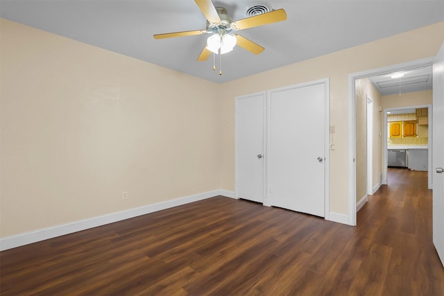 unfurnished bedroom with dark wood-style floors, visible vents, attic access, and baseboards