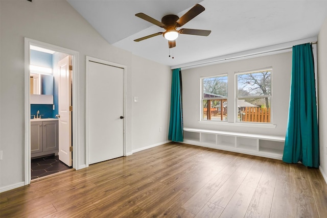 unfurnished bedroom featuring baseboards, a ceiling fan, lofted ceiling, wood finished floors, and ensuite bathroom