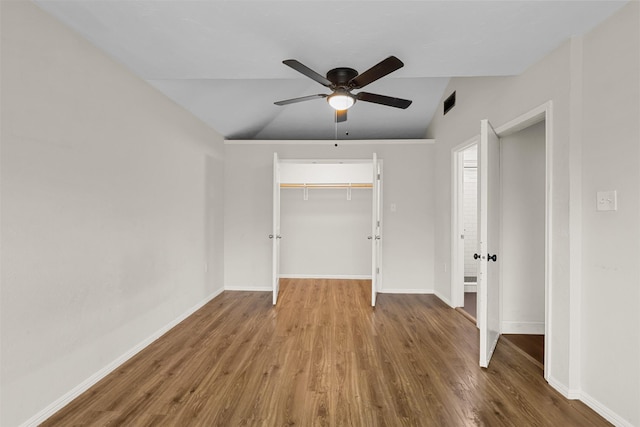 spare room with lofted ceiling, ceiling fan, wood finished floors, visible vents, and baseboards