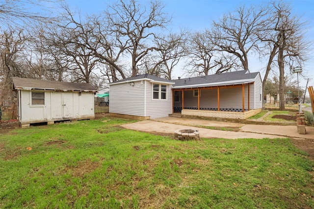 rear view of property featuring an outdoor fire pit, a yard, fence, an outdoor structure, and a patio area