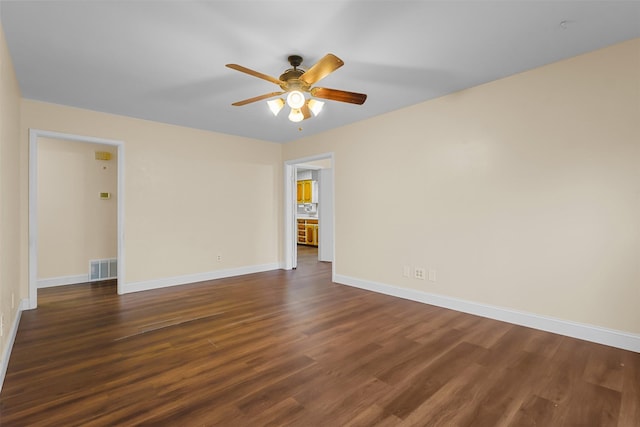 unfurnished room with visible vents, dark wood finished floors, and baseboards