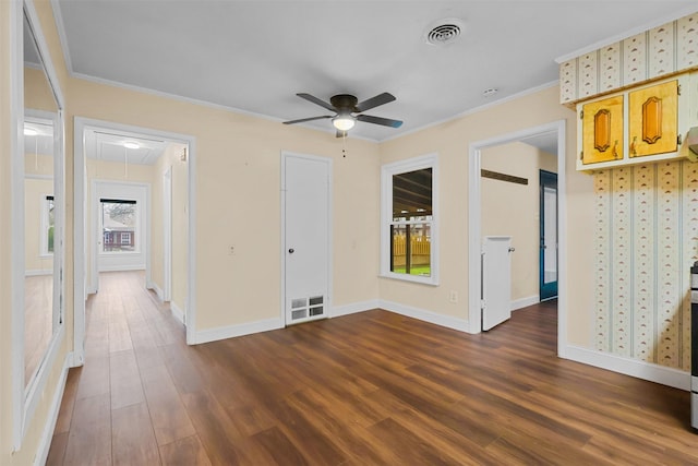 empty room featuring attic access, visible vents, crown molding, and dark wood-style floors