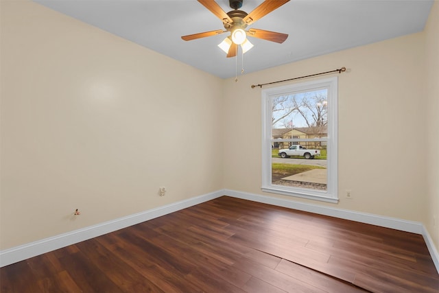 spare room with dark wood finished floors, baseboards, and ceiling fan