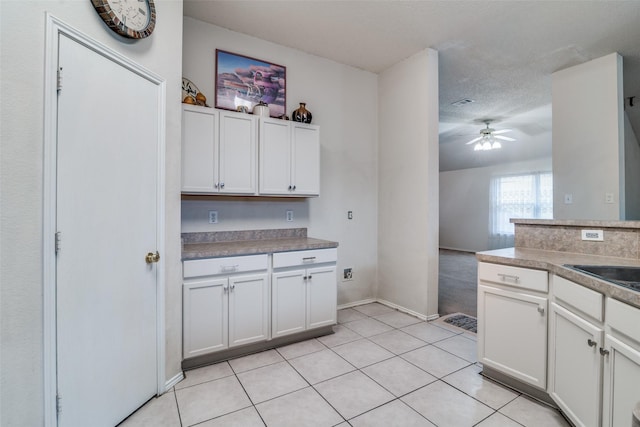 kitchen with light tile patterned flooring, white cabinets, a textured ceiling, and ceiling fan