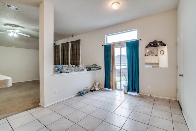 tiled spare room featuring baseboards, a ceiling fan, visible vents, and a textured ceiling