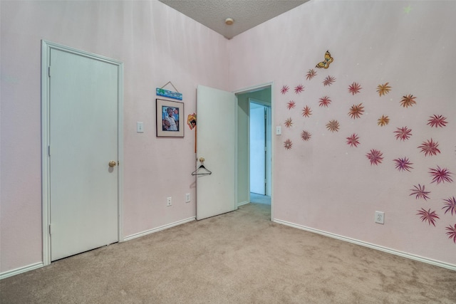 unfurnished bedroom with a textured ceiling, baseboards, and carpet floors