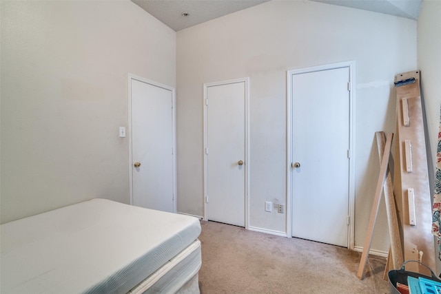 bedroom with light colored carpet and vaulted ceiling