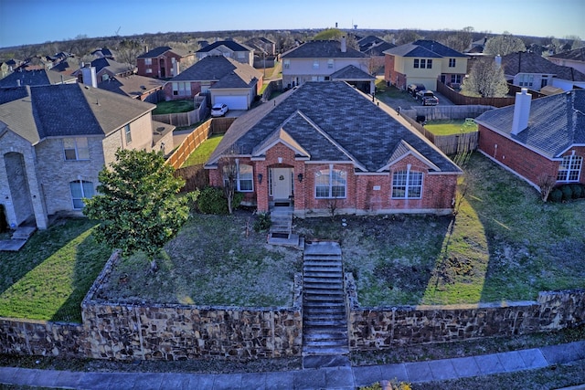 view of front of home with fence, brick siding, and a residential view