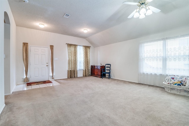 empty room featuring visible vents, ceiling fan, lofted ceiling, carpet flooring, and a textured ceiling