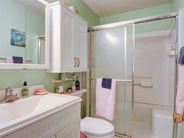 full bathroom with a stall shower, a textured ceiling, toilet, and vanity