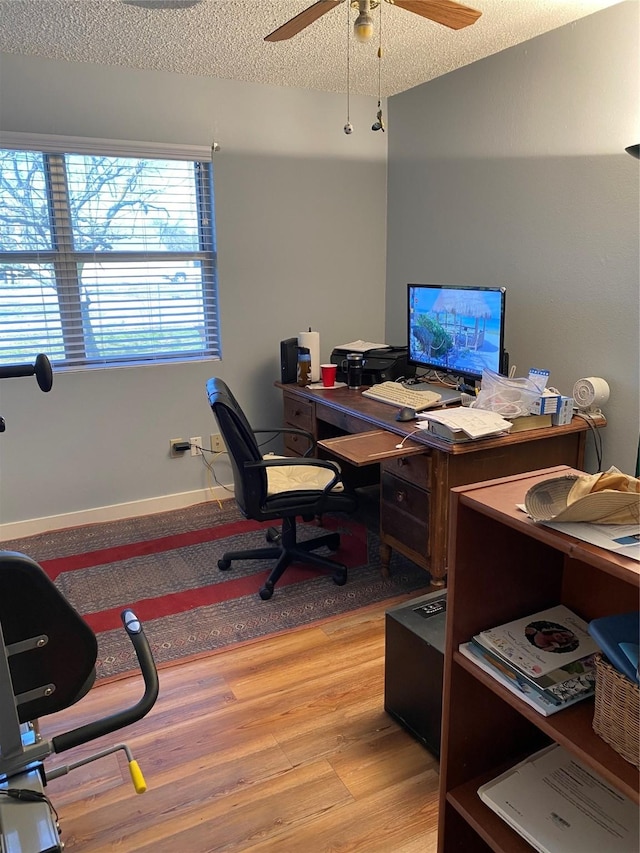 home office featuring a ceiling fan, baseboards, a textured ceiling, and light wood finished floors