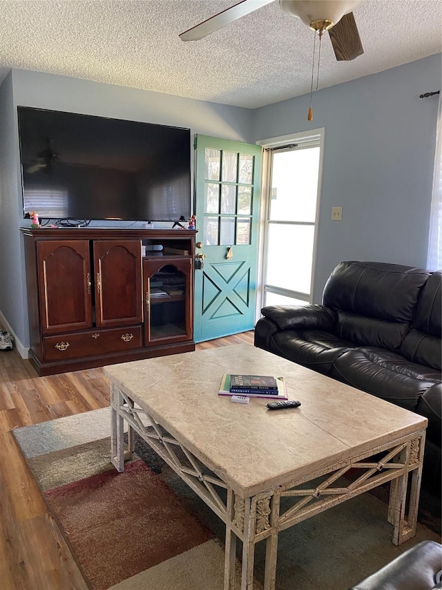 living area with a ceiling fan, light wood-style floors, and a textured ceiling