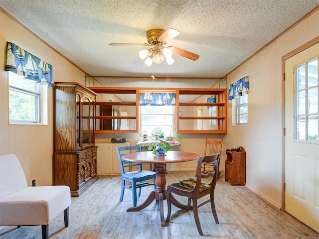 dining room featuring light wood-type flooring, crown molding, a textured ceiling, and ceiling fan