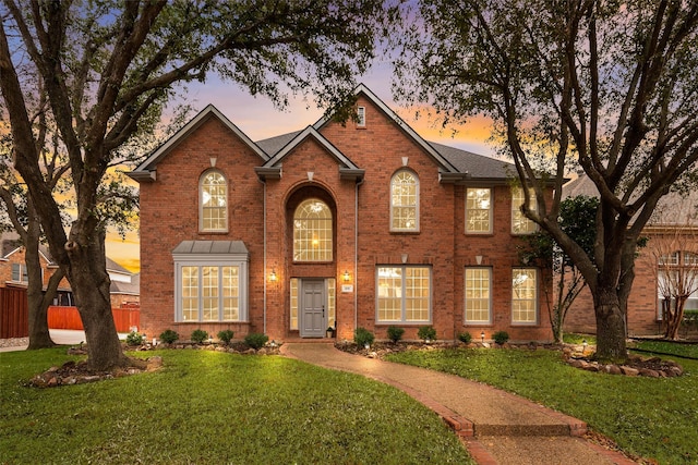 view of front of home featuring fence, a front lawn, and brick siding