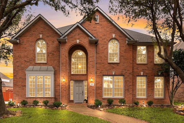 view of front facade featuring brick siding and a front yard