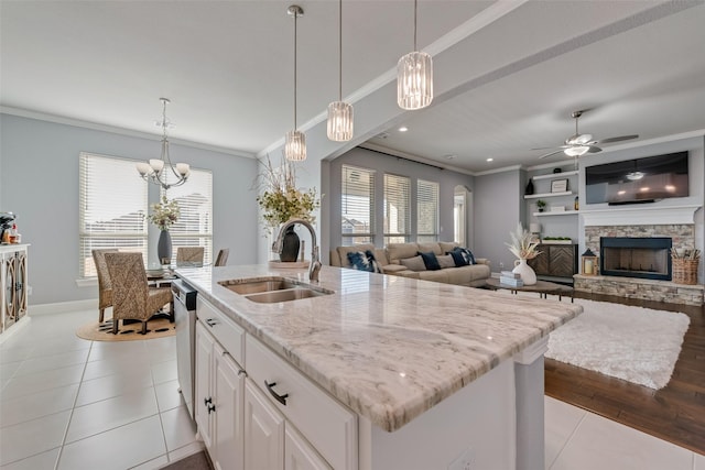 kitchen featuring light stone counters, a fireplace, ornamental molding, a sink, and tile patterned flooring