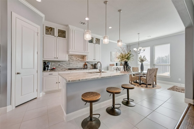 kitchen featuring ornamental molding, visible vents, a sink, and tasteful backsplash