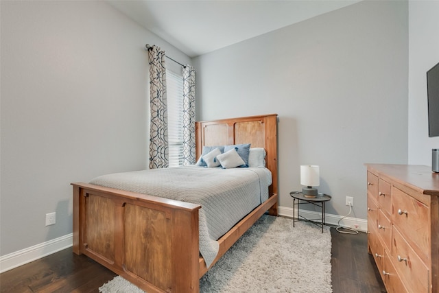 bedroom with dark wood-type flooring and baseboards