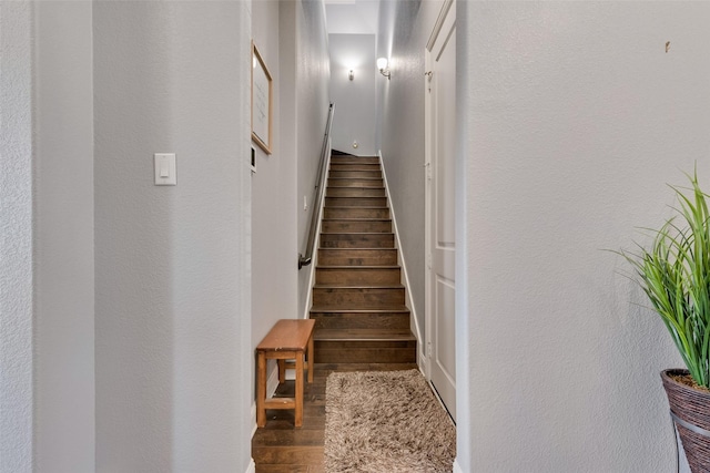 stairs featuring a textured wall and wood finished floors