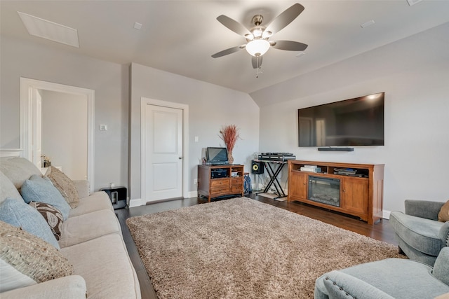 living area featuring vaulted ceiling, dark wood-style flooring, ceiling fan, and baseboards