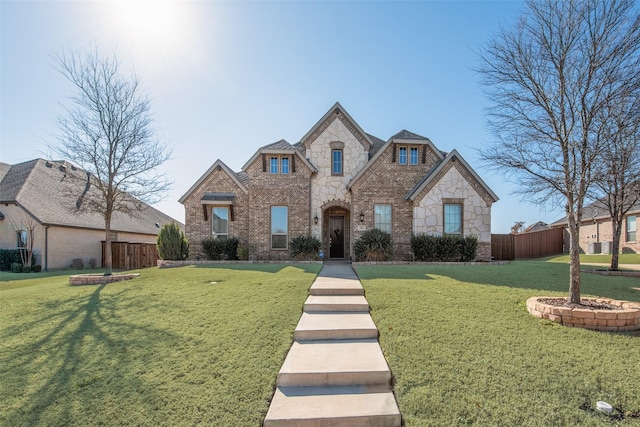 french country style house with stone siding, brick siding, fence, and a front lawn