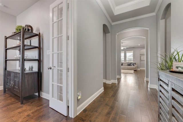 corridor featuring ornamental molding, arched walkways, dark wood-style flooring, and baseboards