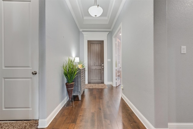 entryway with dark wood-type flooring, a tray ceiling, crown molding, and baseboards