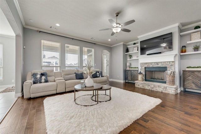 living room with dark wood-style floors, a fireplace, visible vents, ornamental molding, and baseboards