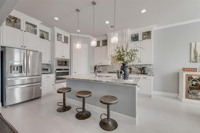 kitchen featuring stainless steel appliances, tasteful backsplash, visible vents, a sink, and an island with sink