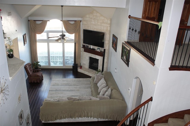 living area with a large fireplace, ceiling fan, and wood finished floors