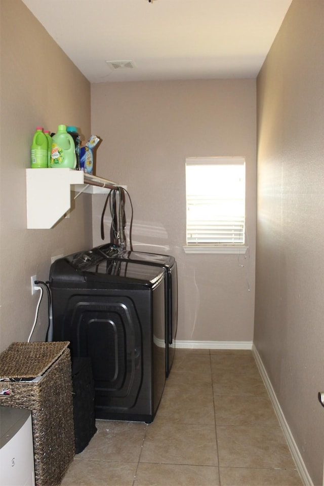 laundry area featuring washing machine and clothes dryer, light tile patterned floors, visible vents, laundry area, and baseboards