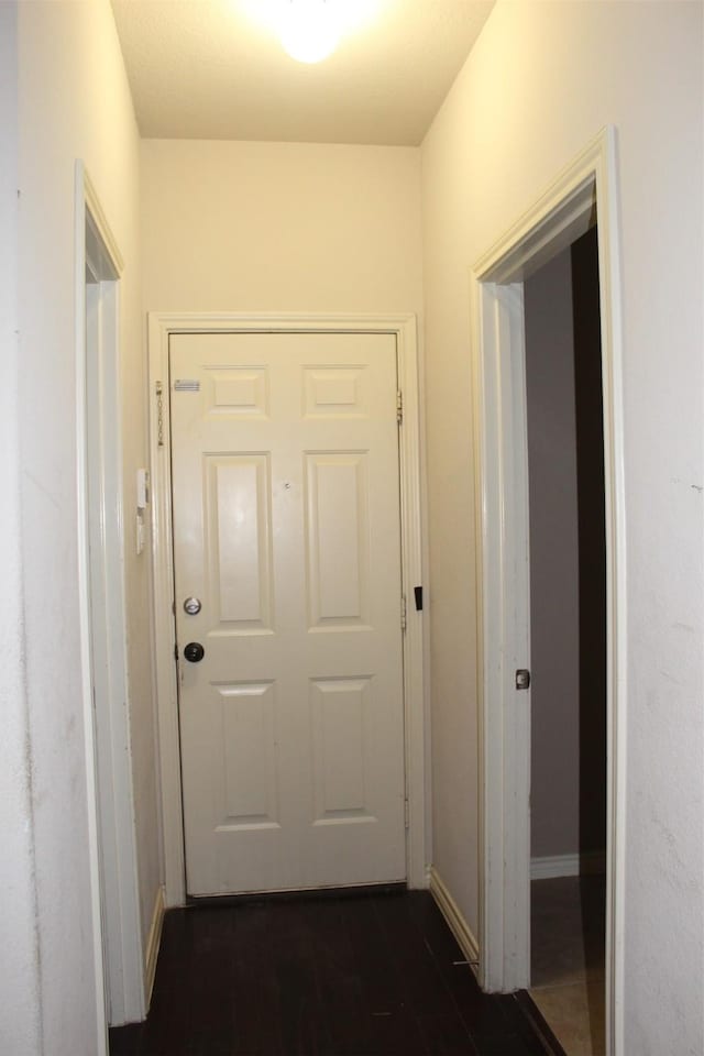 hall with baseboards and dark wood-style flooring