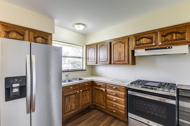 kitchen with dark wood finished floors, appliances with stainless steel finishes, light countertops, under cabinet range hood, and a sink