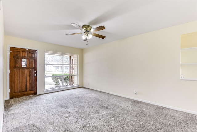 carpeted spare room with baseboards and a ceiling fan