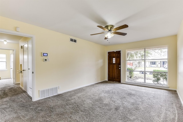 carpeted spare room with baseboards, visible vents, and a healthy amount of sunlight