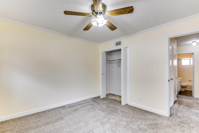 unfurnished bedroom featuring a closet, visible vents, ornamental molding, carpet flooring, and a textured ceiling