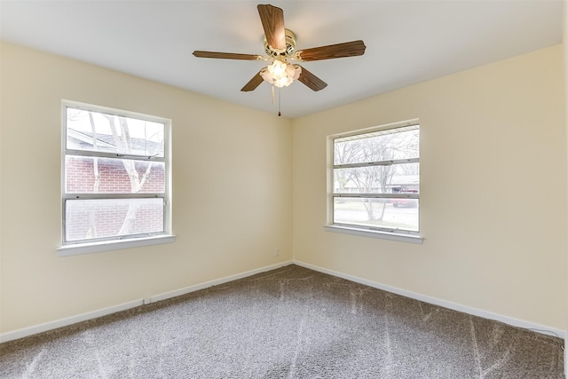 carpeted spare room featuring baseboards and a ceiling fan